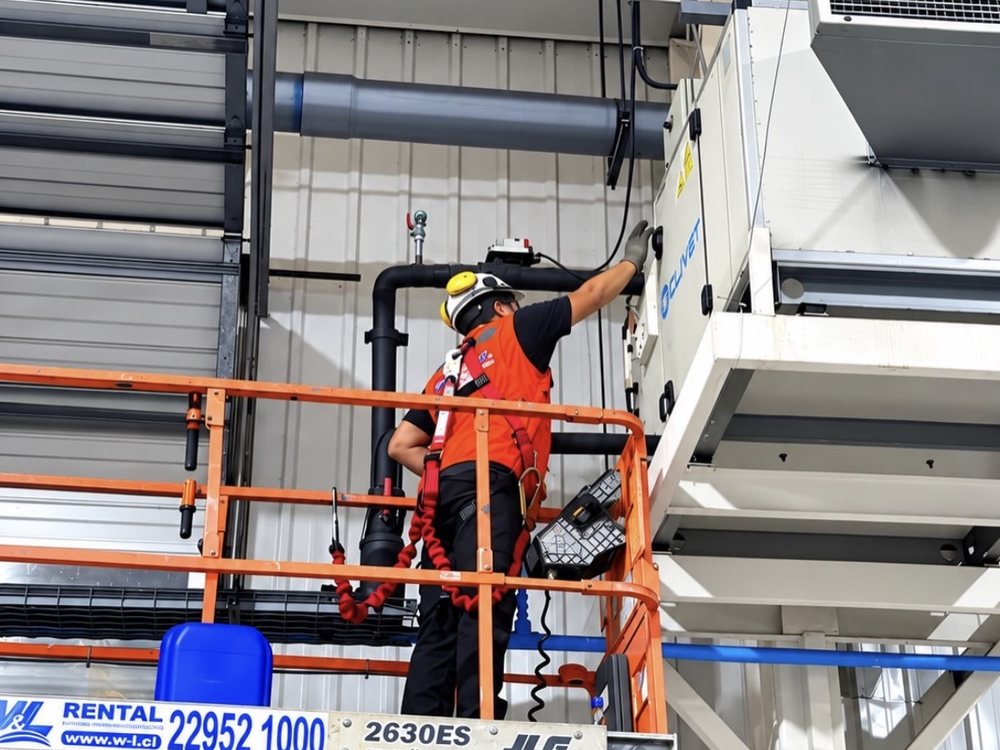 Técnico con arnés en plataforma de tijera durante mantención industrial